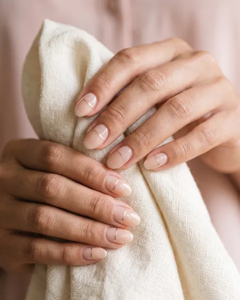Short almond nails in sheer nude with a fine gold line