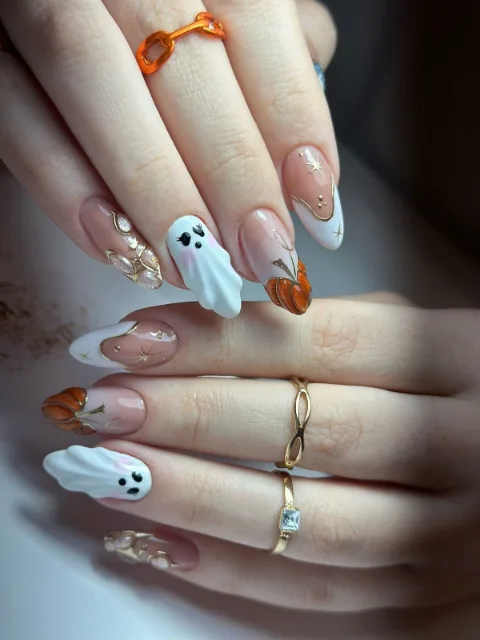 Hands with dark wine nails holding a small pumpkin